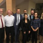 Grupa osób w formalnym stroju pozująca do zdjęcia w pomieszczeniu biurowym